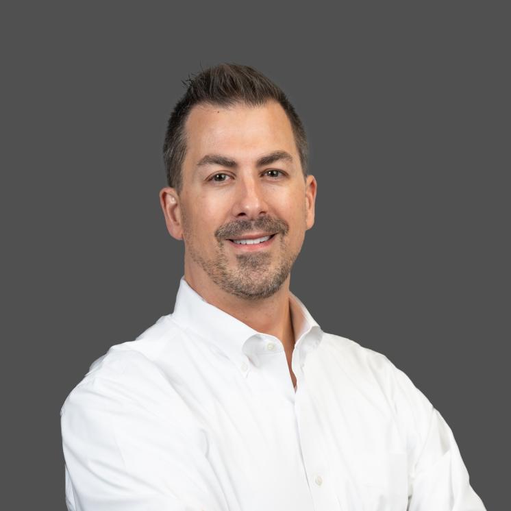 A man in a white button down shirt in front a grey backdrop