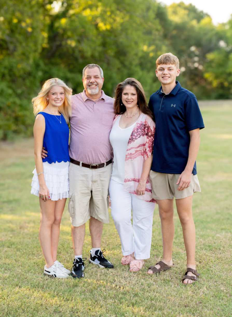 a group of people standing outside for a family photo in grass
