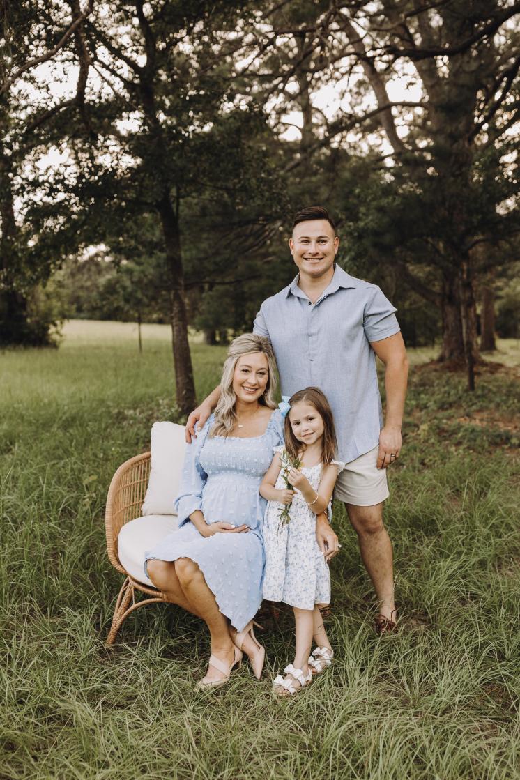 3 people sitting in a chair in a grassy field for a photoshoot