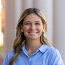 Woman standing in front of white columns on a sunny day.