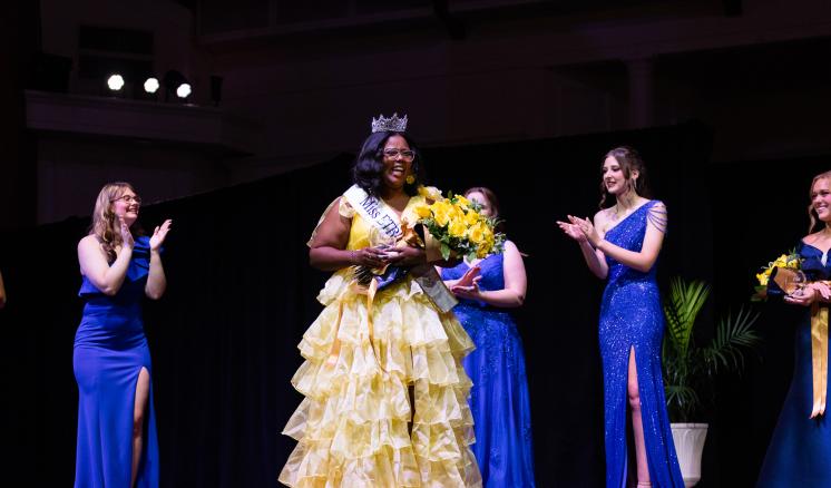 A group of women standing on a stage in formal attire