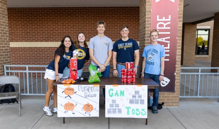 A group of people stood over a fall festival table outside