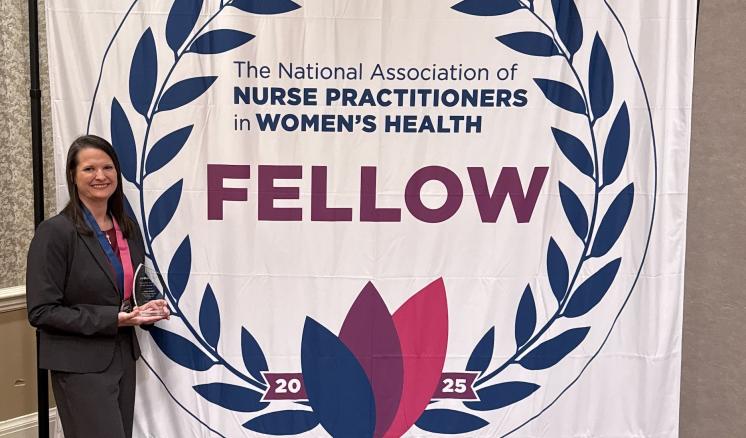A woman in front of a backdrop sign that says the national association of nurse practitioners in womens health