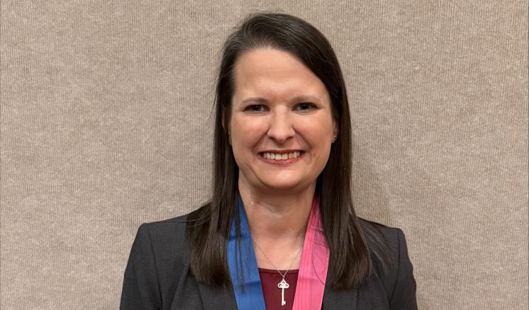 A woman in formal attire holding a lazer engraved glass award
