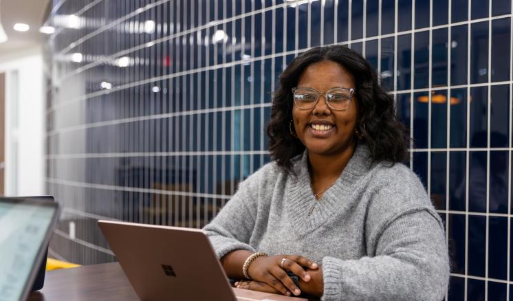 A woman sat at a table with her hands on a laptop