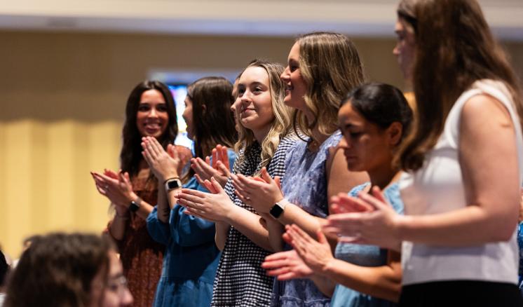 A group of women stood together inside clapping