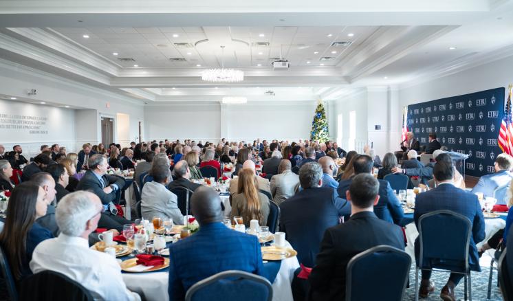 A crowded room of people sitting for a luncheon together