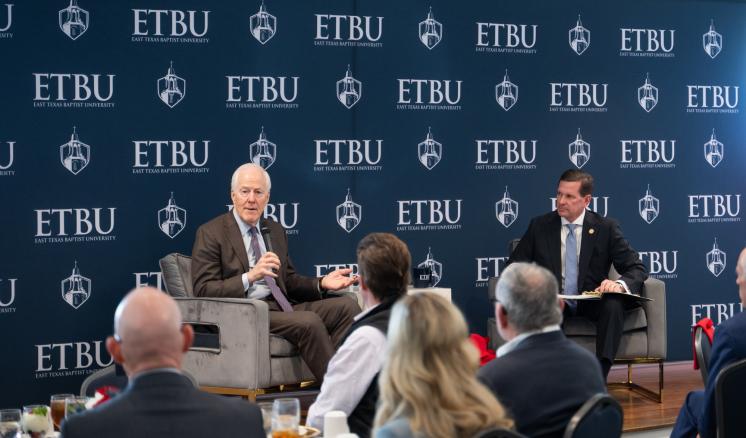 A room of people listening intently to 2 men on a stage talking