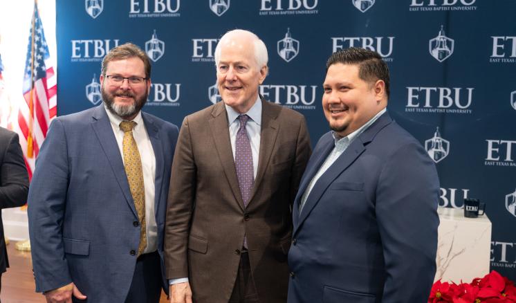 3 men stood together in front of an ETBU backdrop smiling