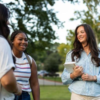 Group of girls talking outside on a green lawn.