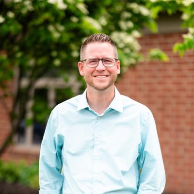 A man outside wearing blue jeans and a button down shirt