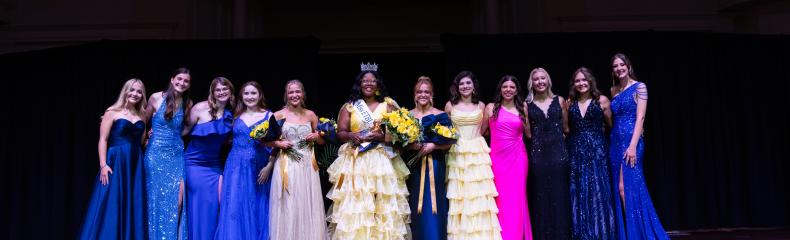 A group of women standing on a stage in formal attire
