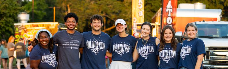 A group of college students standing together outside with ETBU Student Foundation written on their shirts